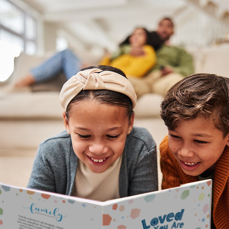 christian parents on couch, kids on carpet, smiling and reading "loved as you are" christian adoption book by steven cohen